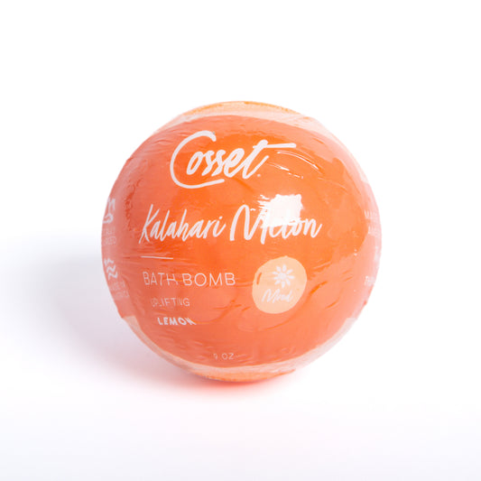 Round, 9 oz orange Kalahari Melon bath bomb wrapped in clear plastic with white text and lemon scent branding.